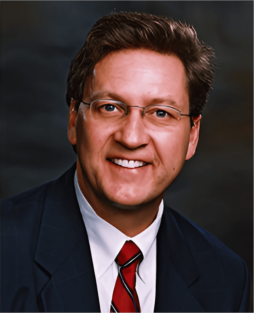 A man in a suit and tie smiling for the camera.