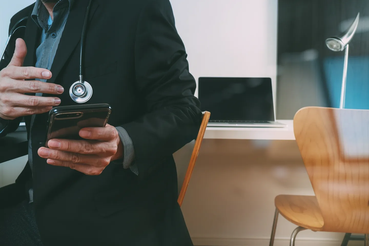 A person in a suit and stethoscope holding a cell phone.