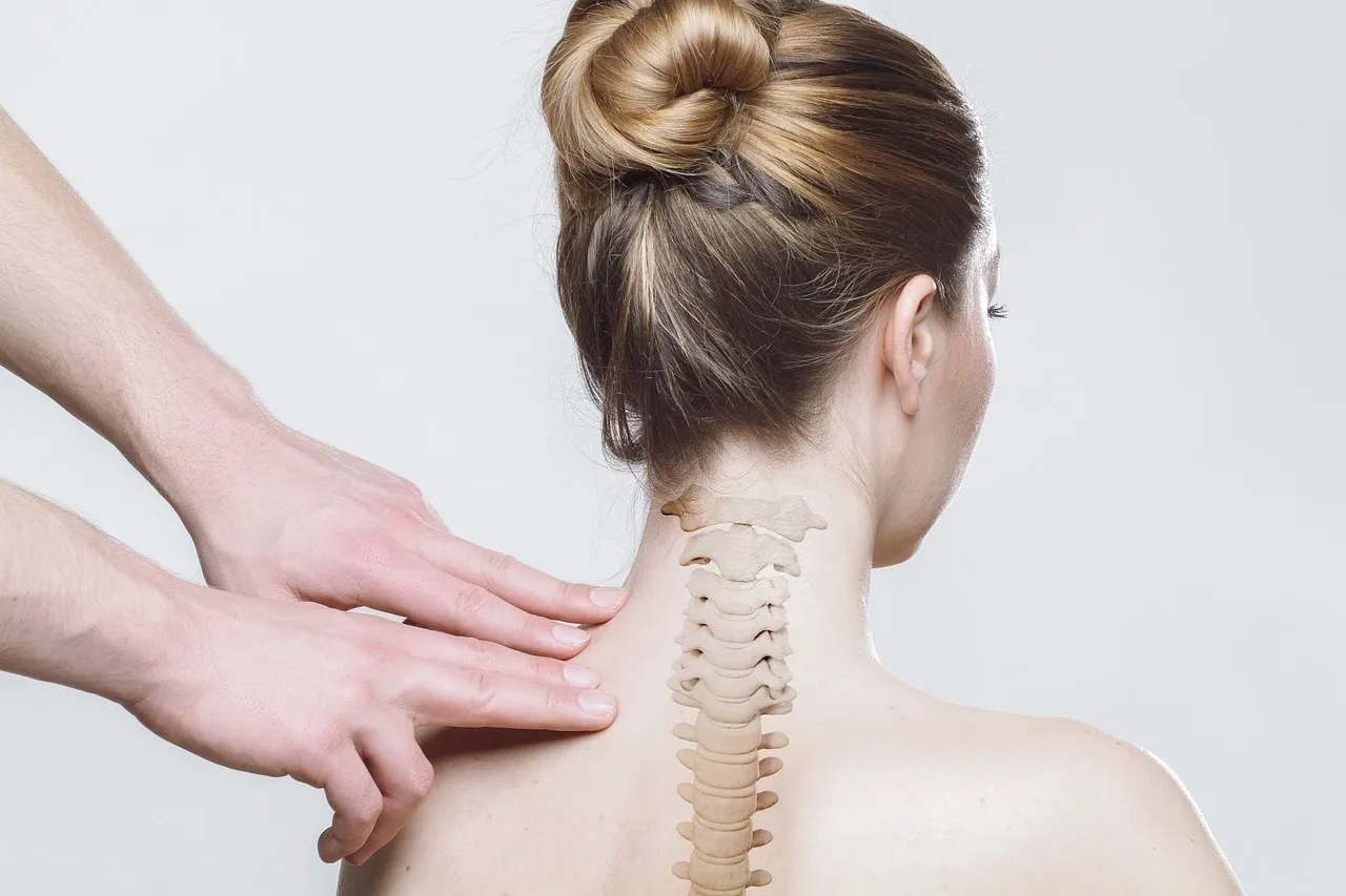 A woman with her back turned and another person touching the back of her neck.